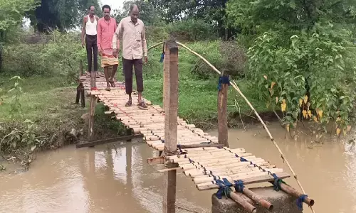 Villagers crossing the stream using a wooden bridge