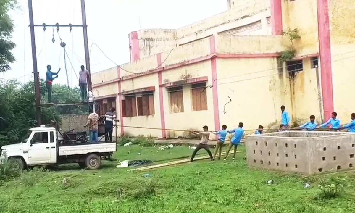 बच्चों से ट्रांसफार्मर खिंचवाते हुए कर्मचारी