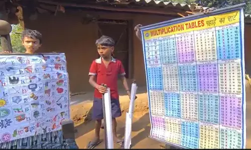 हाथ में वर्णमाला और पहाड़े की चार्ट लिए हुए नेन्द्रा स्कूल के बच्चे